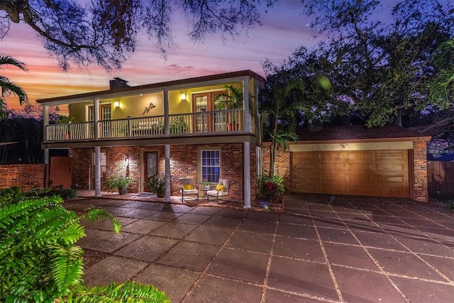 view of front of home featuring a balcony, a garage, concrete driveway, and brick siding