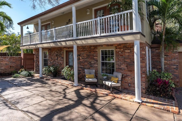 back of property with brick siding, fence, and a balcony