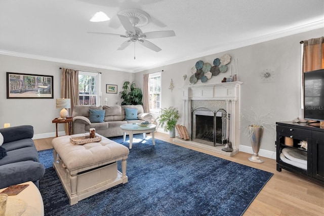 living area with baseboards, ornamental molding, a fireplace with raised hearth, and wood finished floors