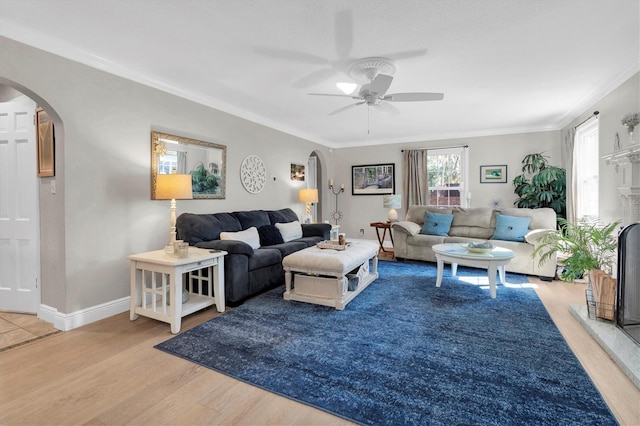 living area featuring arched walkways, baseboards, wood finished floors, and crown molding