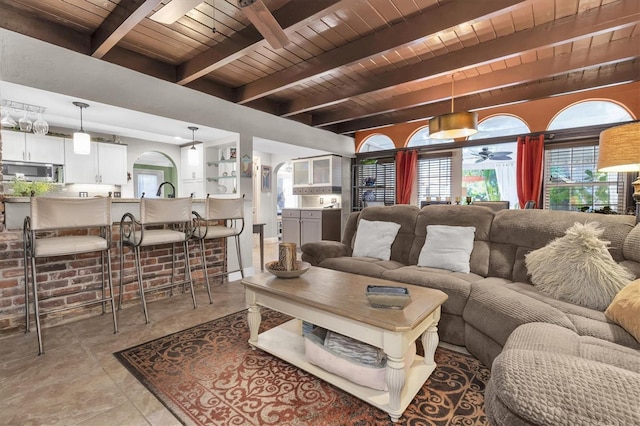 living area featuring wooden ceiling, ceiling fan, light tile patterned floors, and beam ceiling