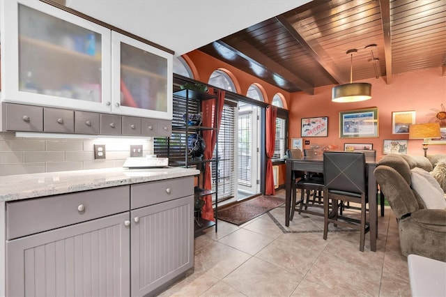 kitchen with beam ceiling, light tile patterned floors, backsplash, gray cabinetry, and wooden ceiling