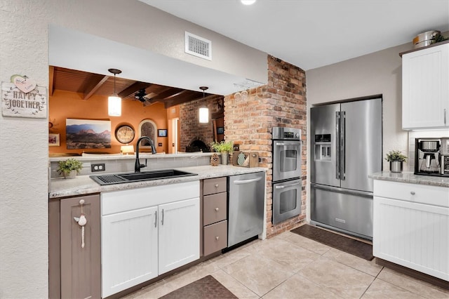 kitchen with visible vents, white cabinets, appliances with stainless steel finishes, beamed ceiling, and a sink