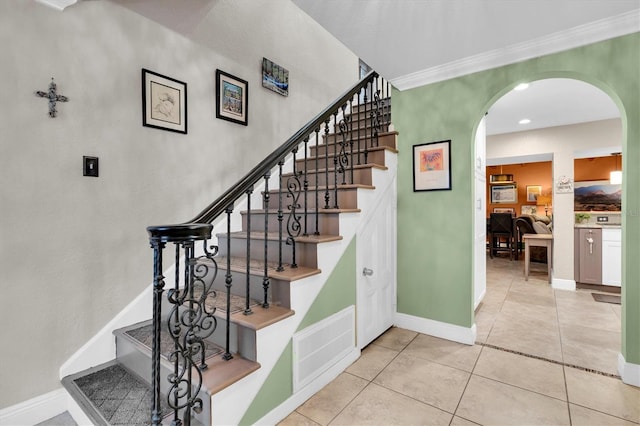 stairway featuring arched walkways, visible vents, baseboards, tile patterned floors, and crown molding