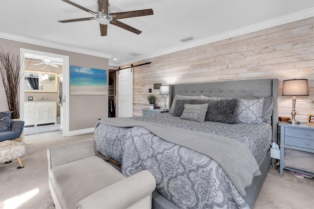 bedroom with carpet, visible vents, a barn door, ornamental molding, and wood walls