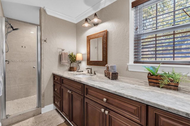 full bath featuring ornamental molding, a textured wall, a shower stall, and vanity