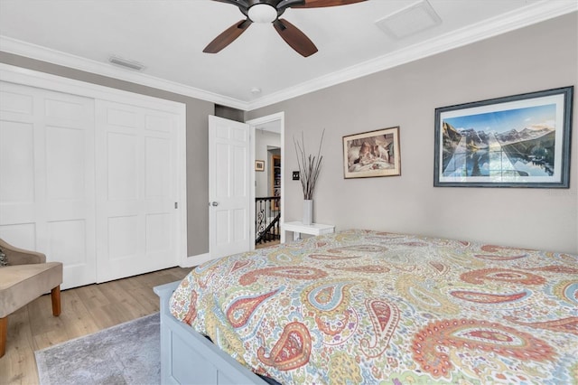 bedroom with ornamental molding, a closet, visible vents, and wood finished floors