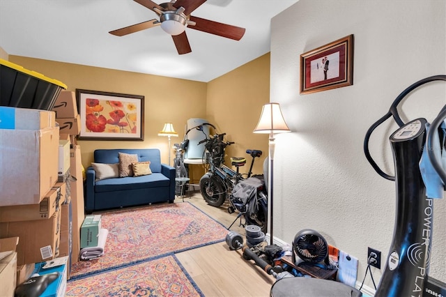 workout room with ceiling fan, a textured wall, wood finished floors, and baseboards