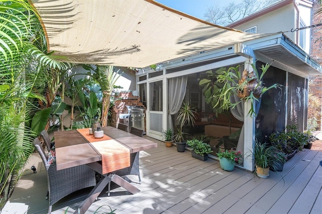 wooden terrace featuring outdoor dining area, area for grilling, and a sunroom