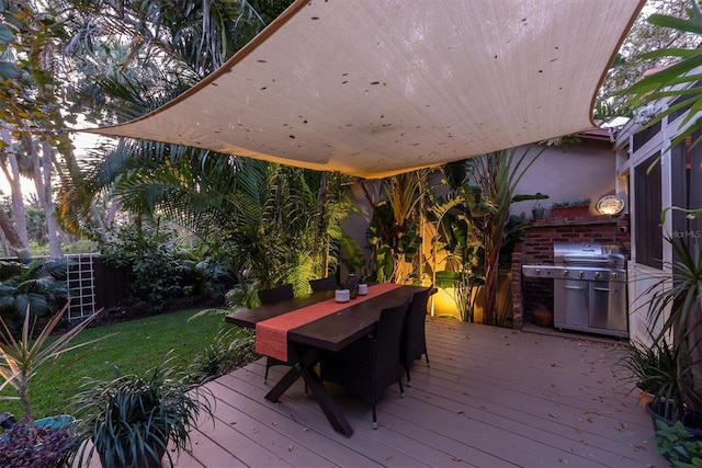 deck featuring outdoor dining space, a lawn, and area for grilling