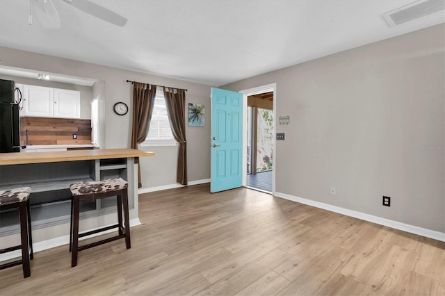 interior space with visible vents, white cabinets, butcher block counters, light wood-style floors, and a kitchen bar