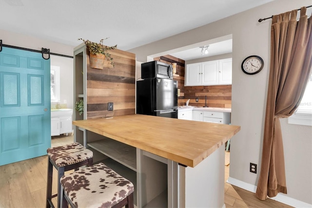 kitchen featuring white cabinetry, wooden counters, freestanding refrigerator, light wood finished floors, and stainless steel microwave