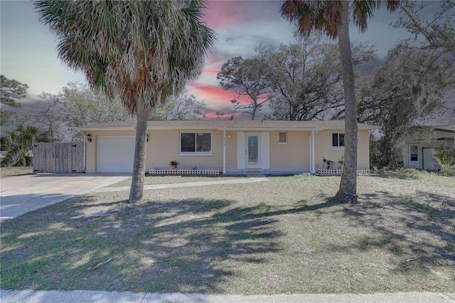 single story home with a garage, concrete driveway, and fence