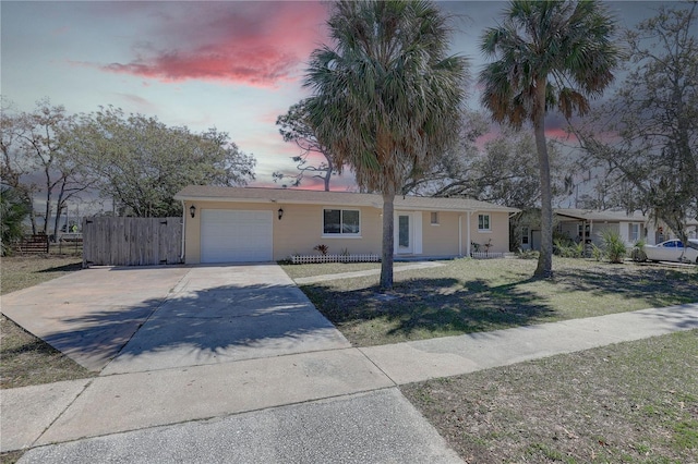 single story home with concrete driveway, an attached garage, fence, and a front yard