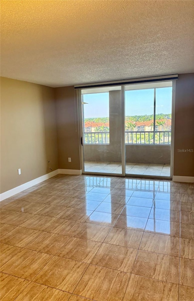 spare room with floor to ceiling windows, a textured ceiling, and baseboards