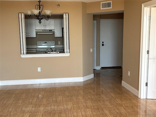 spare room with visible vents, a sink, baseboards, and an inviting chandelier