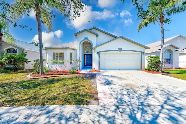 view of front facade with concrete driveway, a front yard, an attached garage, and stucco siding