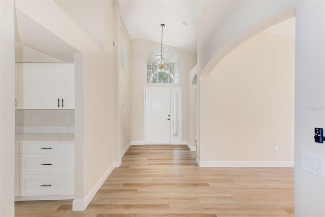 foyer entrance with light wood-style floors, baseboards, and high vaulted ceiling