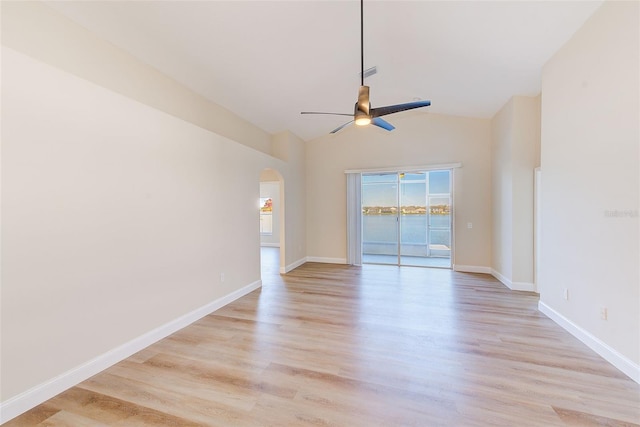 spare room with baseboards, arched walkways, ceiling fan, vaulted ceiling, and light wood-type flooring