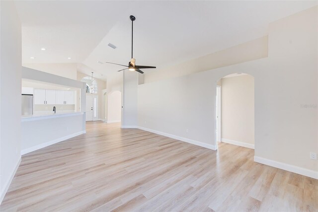 unfurnished living room featuring light wood-type flooring, arched walkways, and a ceiling fan