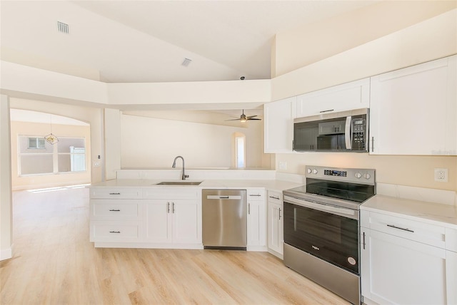 kitchen with lofted ceiling, visible vents, appliances with stainless steel finishes, white cabinets, and a sink