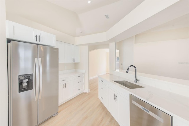 kitchen featuring a sink, white cabinets, light countertops, appliances with stainless steel finishes, and light wood-type flooring