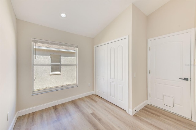 unfurnished bedroom featuring lofted ceiling, light wood finished floors, a closet, and baseboards