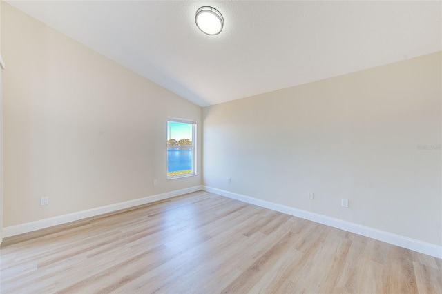 unfurnished room featuring light wood-type flooring, baseboards, and lofted ceiling