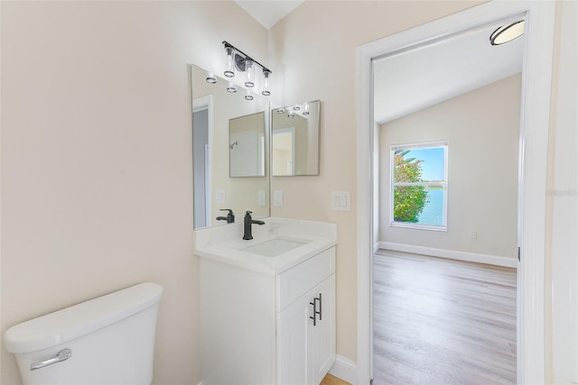 bathroom with baseboards, toilet, wood finished floors, vaulted ceiling, and vanity