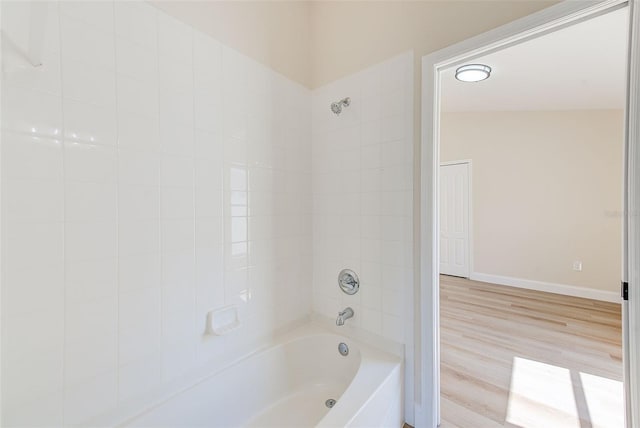 bathroom with tub / shower combination, wood finished floors, and baseboards