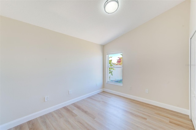 unfurnished room with light wood-type flooring, baseboards, and vaulted ceiling