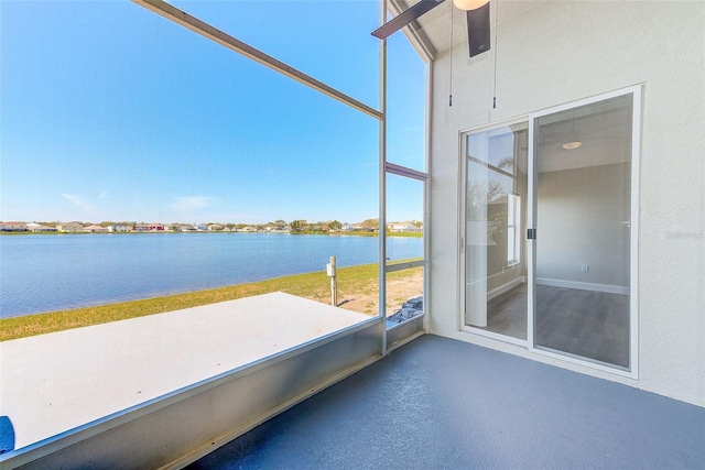 unfurnished sunroom featuring a water view and ceiling fan