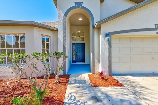 doorway to property with a garage, roof with shingles, and stucco siding