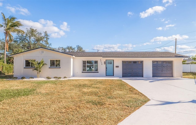 single story home featuring concrete driveway, brick siding, an attached garage, and a front lawn