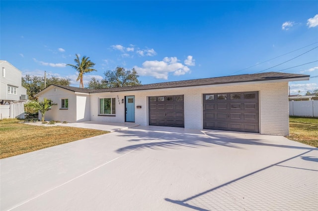 ranch-style home featuring a garage, brick siding, fence, concrete driveway, and a front yard