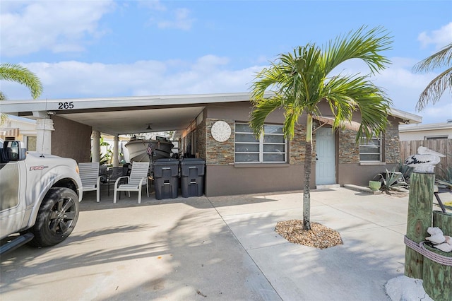 view of front facade featuring driveway, a carport, fence, and stucco siding