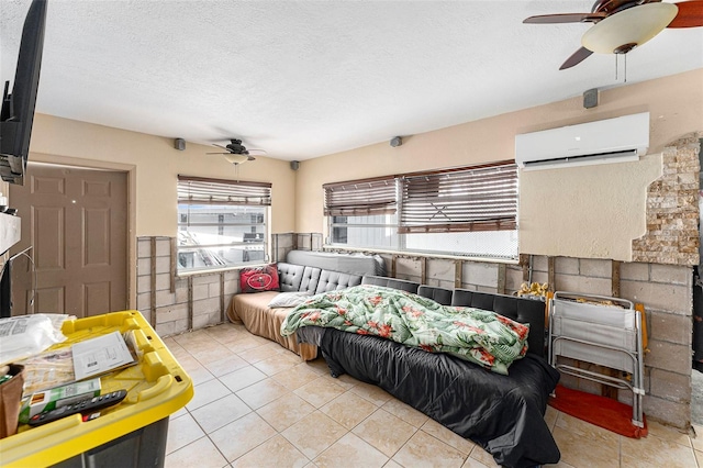 tiled bedroom with a ceiling fan, an AC wall unit, a wainscoted wall, and a textured ceiling