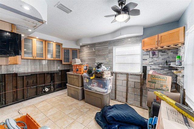 kitchen featuring glass insert cabinets, visible vents, ceiling fan, and a textured ceiling