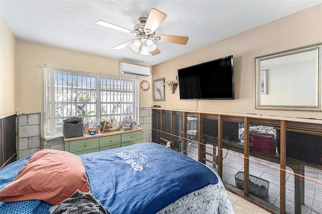 bedroom with a textured ceiling, ceiling fan, a wainscoted wall, an AC wall unit, and tile patterned floors