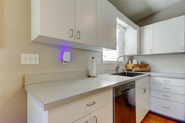 kitchen featuring light countertops, dishwasher, a sink, and white cabinetry