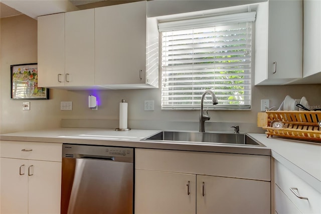 kitchen with a sink, light countertops, stainless steel dishwasher, and white cabinetry