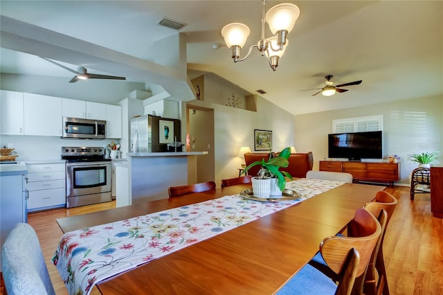 dining space featuring light wood-type flooring, visible vents, ceiling fan with notable chandelier, and lofted ceiling
