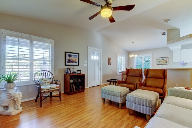 living area featuring ceiling fan with notable chandelier, light wood finished floors, lofted ceiling, and plenty of natural light