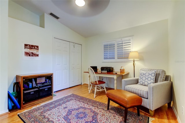 office space featuring lofted ceiling, visible vents, baseboards, and wood finished floors