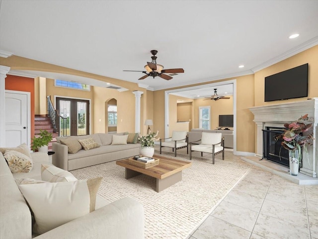 living room with ornamental molding, plenty of natural light, a glass covered fireplace, and decorative columns