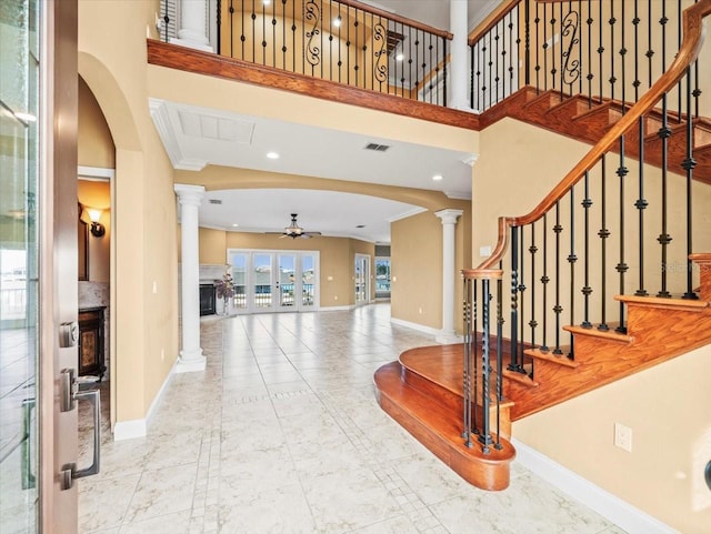 entryway featuring baseboards, visible vents, ceiling fan, and ornate columns