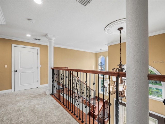 hallway featuring crown molding, ornate columns, visible vents, carpet flooring, and baseboards