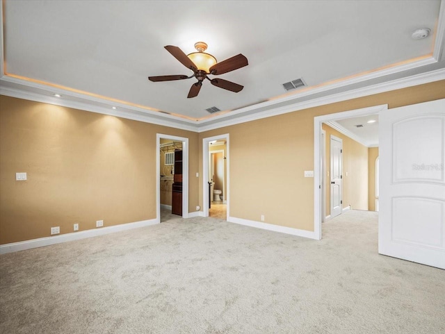 spare room featuring baseboards, a tray ceiling, visible vents, and crown molding