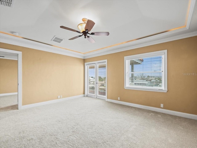 carpeted spare room featuring a raised ceiling, visible vents, and crown molding