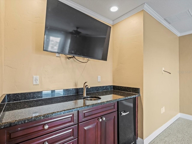 kitchen featuring baseboards, dark stone counters, dark brown cabinets, and crown molding